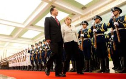 La canciller alemana, Angela Merkel (c), y el primer ministro chino, Wen Jiabao (i), caminan a lo largo de una guardia de honor a su llegada este jueves a Pekín.