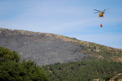 Un helicóptero transporta agua para vertirla sobre el incendio forestal originado en el término municipal de Robledo de Chavela.