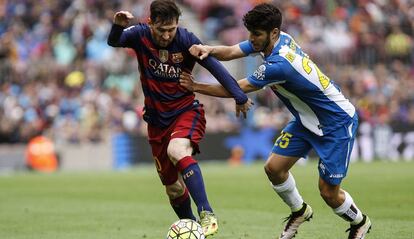 Asesnsio intenta frenar a Messi, en el último derbi catalán.