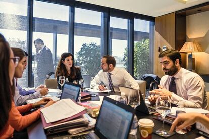 Una escena habitual antes del closing de una operación. Ordenadores. Carpetas. Cafeína. “Es una inversión en un grupo español muy grande y con muchas filiales”, explica Mariana Norton, socia de Cuatrecasas, Gonçalves Pereira, en el centro de la imagen. Se oyen cosas como: “Nos han confirmado que no han suscrito las cláusulas suspensivas”. Mencionan a un inversor mexicano. Hablan del “waiver de los bancos”. De una reunión pendiente con Garrigues. De los votos en el consejo de administración. De si llegan o no los fondos. Del poder para la firma. Y de alguien que es “muy especialito con los restaurantes”.