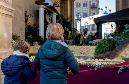 Unos niños contemplan el belén colocado en el Ayuntamiento de Sevilla.