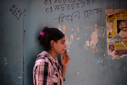 La trabajadora sexual Munni fuma un cigarrillo fuera de su habitación antes de atender a un cliente en el burdel de Kandapara, en Tangail. 