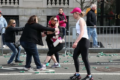 Una participante del maratón de Boston se abraza a otras tres mujeres.