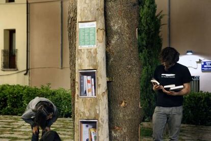 Uns joves consulten llibres d'intercanvi en un dels punts de l'Arllibre instal·lats a Terrassa.