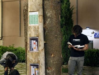 Uns joves consulten llibres d'intercanvi en un dels punts de l'Arllibre instal·lats a Terrassa.