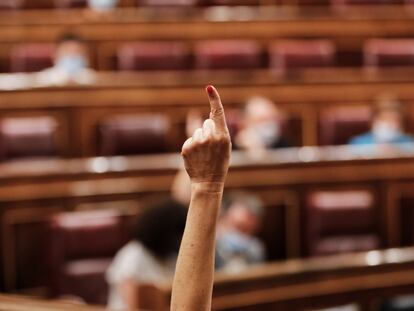 Una diputada marca, con su dedo, el sentido del voto de su partido en el Congreso de los Diputados.