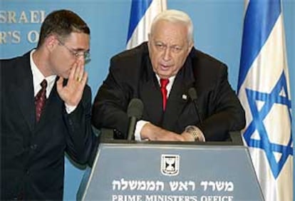 El primer ministro israelí, Ariel Sharon, escucha un comentario de su asesor de prensa.
