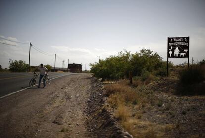 Un hombre empuja una bicicleta rota en los límites de la ciudad de Truth or Consequences, Nuevo México.