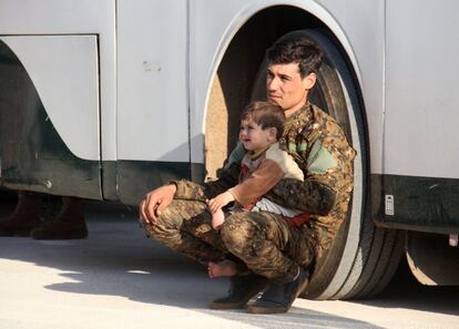 Un combatiente sirio pro-gobierno se sienta con un niño en Alepo (Siria).
