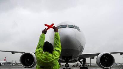 Una técnica de operaciones (TOAM) señaliza a un avión en el aeropuerto brasileño de Guarulhos. 