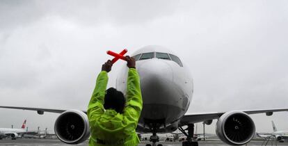 Una técnica de operaciones (TOAM) señaliza a un avión en el aeropuerto brasileño de Guarulhos.