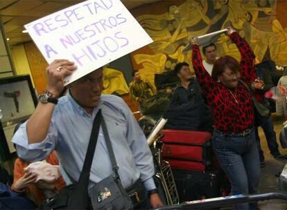 Varios de los pasajeros ecuatorianos exhiben carteles de protesta en el aeropuerto de Barajas.