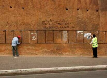 Dos empleados retiran los carteles electorales de un muro del palacio real de Rabat.