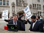 Uber drivers of the (ADCU), App Drivers & Couriers Union, celebrate as they listen to the court decision on a tablet computer outside the Supreme Court in London, Friday, Feb. 19, 2021.  The U.K. Supreme Court ruled Friday that Uber drivers should be classed as “workers” and not self employed.(AP Photo/Frank Augstein)