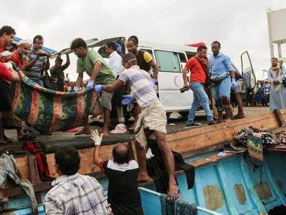 Varios yemen&iacute;es recogen un cad&aacute;ver de un migrante somal&iacute;, en marzo en el puerto de Hodeida.