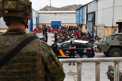 Agentes de la Policía Nacional y militares vigilan a cientos de inmigrantes tras su llegada este martes a Ceuta.