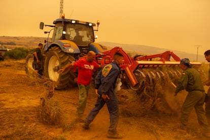 Un grupo de voluntarios y vecinos prepara un tractor para hacer cortafuegos.