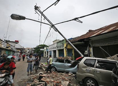 Supervivientes de la tragedia observan coches destrozados por farolas rotas y escombros de casas sobre ellos.