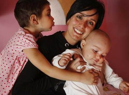 Esther González sostiene a su hija pequeña Izel mientras Erine las besa en su casa de Sant Joan de Vilatorrada (Barcelona).