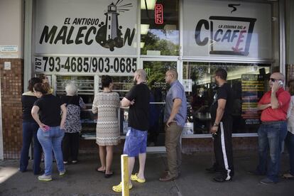 Clientes ante la puerta de una de las pocas cafeterías abiertas en la avenida Roosevelt, en San Juan.