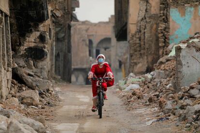 Una mujer vestida de Papa Noel monta en su bicicleta en la ciudad vieja de Mosul (Irak), el 18 de diciembre.