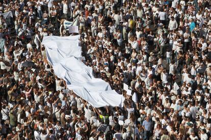 Una gran bandera blanca es llevada por los manifestantes en la plaza de Colón de Madrid.
