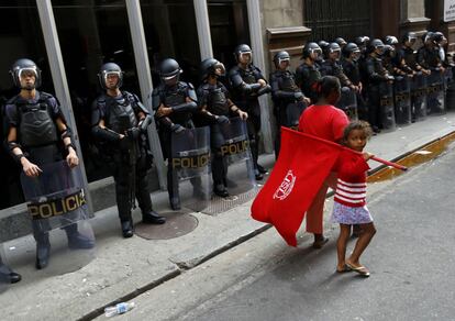 Una niña con una bandera pasa delante de un cordón policial durante una jornada de protesta de los trabajadores del metro en Sao Paulo, Brasil. 9 de junio 2014.