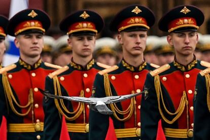 Una paloma vuela cerca de unos soldados de guardia de honor susos antes del Día de la Victoria en la Plaza Roja de Moscú, Rusia.