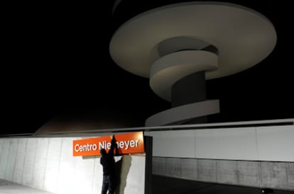 Un operario retira el letrero del Centro de Niemeyer cuya gestión pasará a manos del Principado de Asturias, por lo que no podrá conservar el nombre