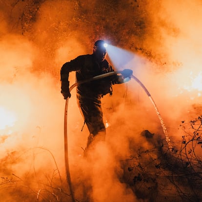 RIBADAVIA, OURENSE, GALICIA, SPAIN - AUGUST 18: A forest brigadier uses a hose to extinguish flames during a wildfire in Ribadavia, Ourense, Galicia, Spain on August 18, 2025. (Photo by Pedro Pascual/Anadolu via Getty Images)