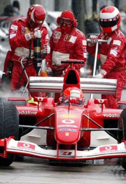 Los operarios de Ferrari revisan el coche de Michael Schumacher.