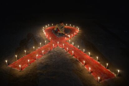 Una trabajadora sexual enciende velas junto a un gran lazo rojo en Siliguri (India).
