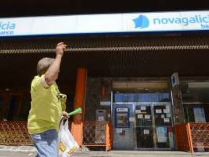 Una afectada por las participaciones preferentes y subordinadas de Novagalicia Banco pasa ante una sucursal de la entidad durante una manifestación. EFE/Archivo