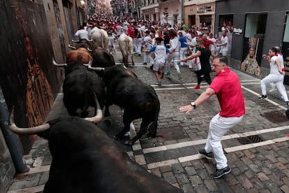 Los toros de la ganadería de Fuente Ymbro pasan por la curva de Mercaderes y enfilan la calle de la Estafeta en el cuarto encierro de los Sanfermines.