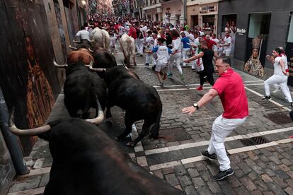 Los toros de la ganadería de Fuente Ymbro pasan por la curva de Mercaderes y enfilan la calle de la Estafeta en el cuarto encierro de los Sanfermines.