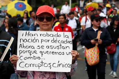 Una mujer sostiene un cartel con la frase "Han robado la nación por décadas. Ahora se asustan porque queremos un cambio... corruptos, cínicos", durante la manifestación de este martes en Bogotá. 