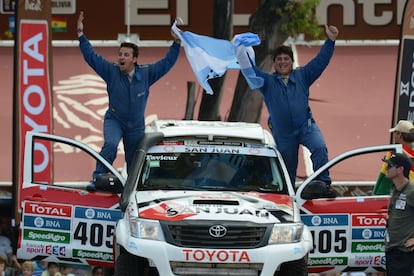 El conductor Juan Gabriel Abarca (d) y su copiloto Juan Varela de Argentina con su bandera nacional a la salida.
