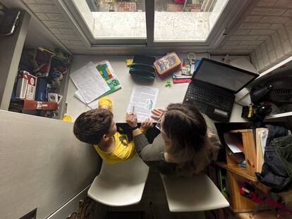 Un niño estudia y hace los deberes en casa con la ayuda de su madre.