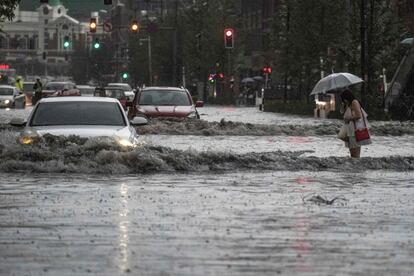 Una mujer intenta cruzar una calle inundada tras las fuertes lluvias que han caído en Shenyang, en la provincia de Liaoning (China).