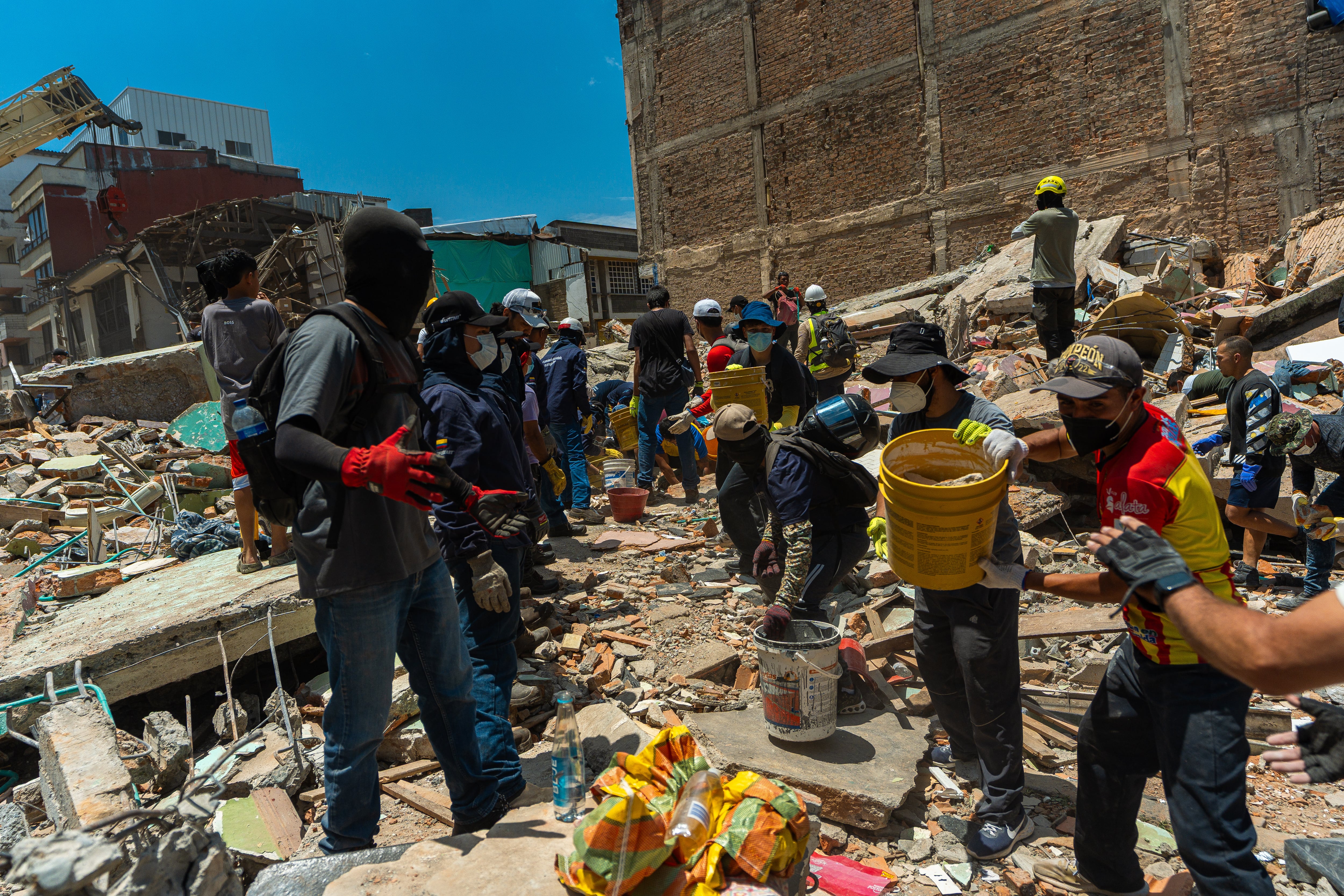 Un grupo de personas ayuda a levantar escombros de un edificio afectado por el terremoto en Pereira, Colombia, el martes.