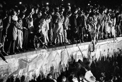 En la imagen, los ciudadanos celebran la apertura del Muro mientras se suben sobre él, a la altura de la puerta de Brandenburgo