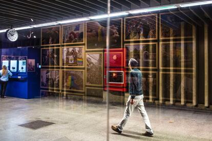 As paredes de vidro do espaço refletem os passantes e misturam as obras da exibição com os corredores da estação.