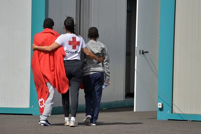 Una trabajadora de la Cruz Roja, junto a dos menores migrantes, en El Hierro el 15 de julio.