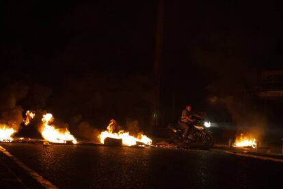 Un hombre armado ahuyenta a manifestantes durante una protesta nocturna en Maracaibo.