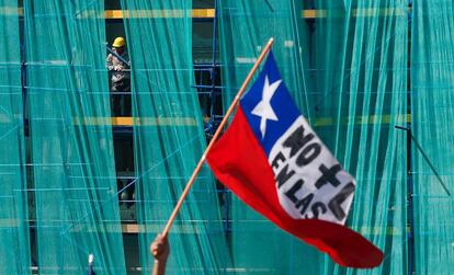 Un obrero observa desde un andamio durante una protesta de funcionarios contra la nueva reforma laboral, en Santiago de Chile.