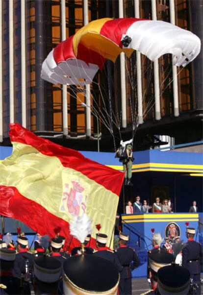 Oficialmente el acto ha comenzado con la llegada de los Reyes, que han sido recibidos con honores militares de Ordenanza. El Rey ha pasado revista a las tropas y han comenzado los actos del desfile. El primero, la llegada de la bandera, que ha traído desde el cielo un miembro de la Brigada Paracaidista, que ha saltado junto a varios compañeros para realizar el acto de izado de la enseña.