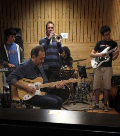 Joaquín Chacón, sentado con una guitarra, en una clase práctica en la Escuela de Música Creativa.