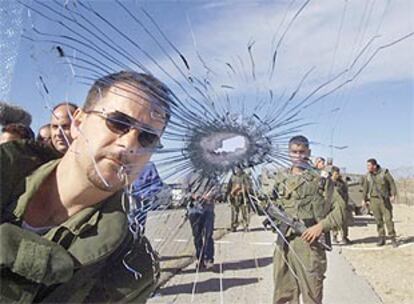 Solados israelíes miran el balazo que, atravesando el cristal, ha acabado con la vida de un colono esta mañana en un asentamiento al norte de Gaza.
