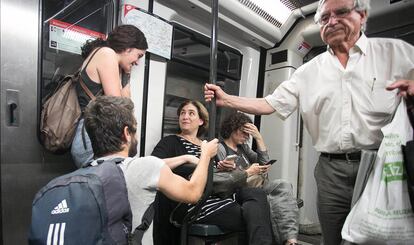 Ciudadanos conversan y dan animo a la nueva alcaldesa de Barcelona, Ada Colau, mientras ella trabaja con su móvil en el interior del Metro de Barcelona, en el primer día de trabajo como alcaldesa, el 15 de junio de 2015.