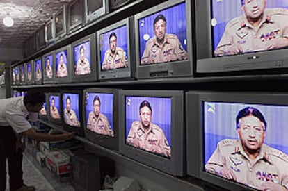 El propietario de una tienda de electrodomésticos de Islamabad regula la imagen de un televisor durante el discurso del presidente Musharraf.
